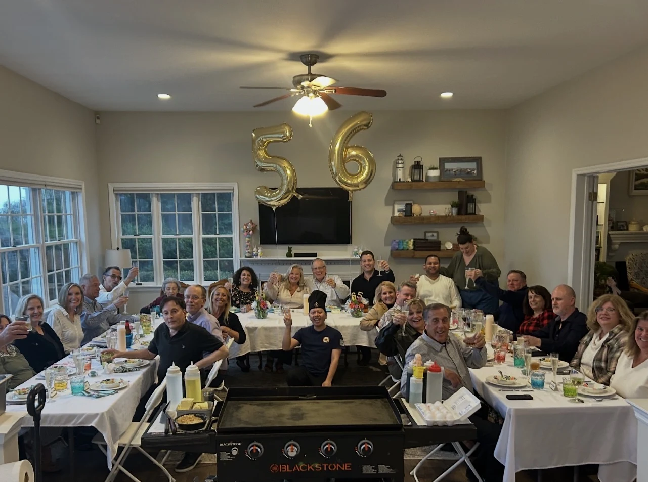 Guests raising their glasses at a birthday dinner with gold birthday balloons