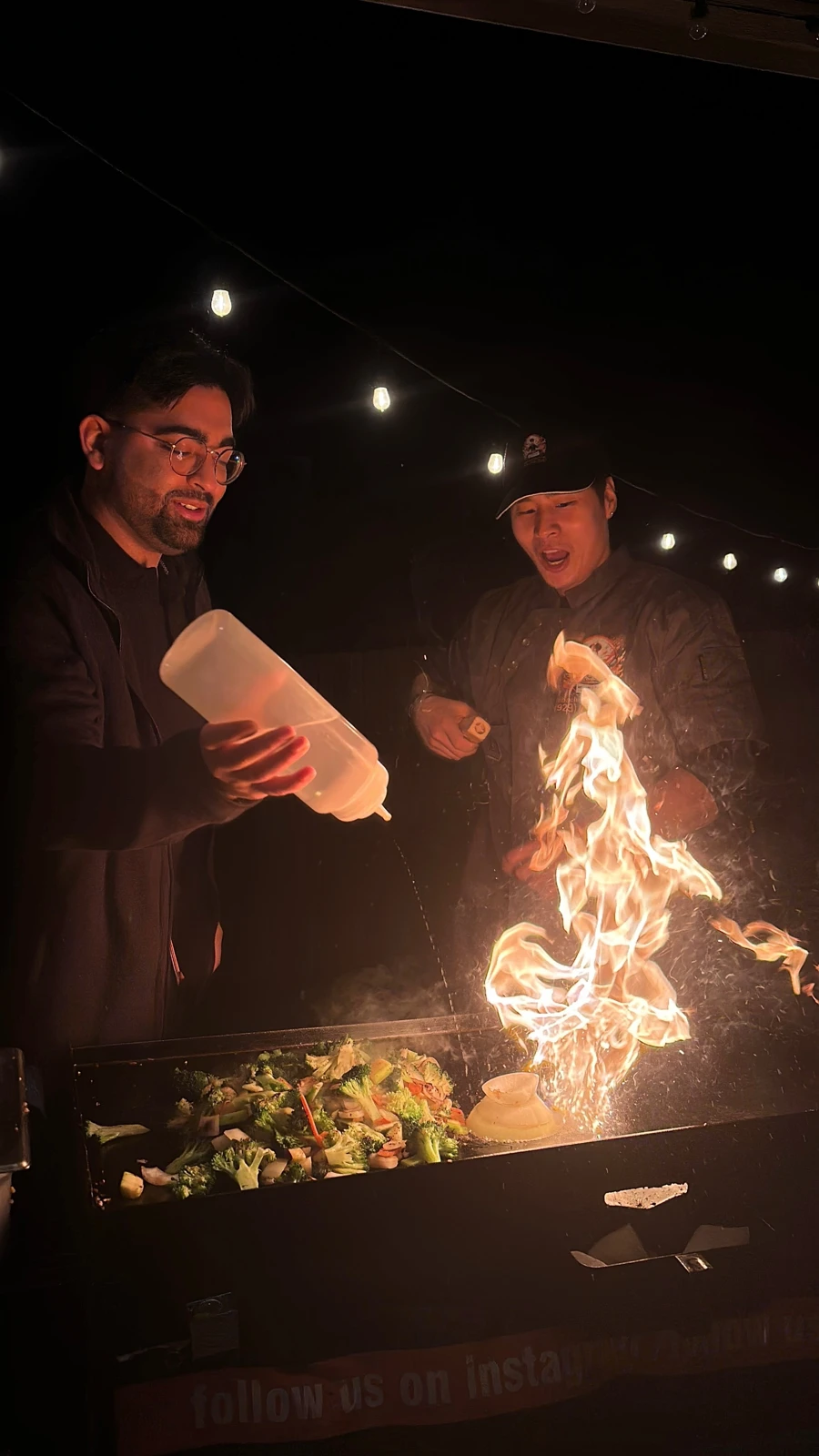 A hibachi chef preparing fresh food with a guest beside the grill